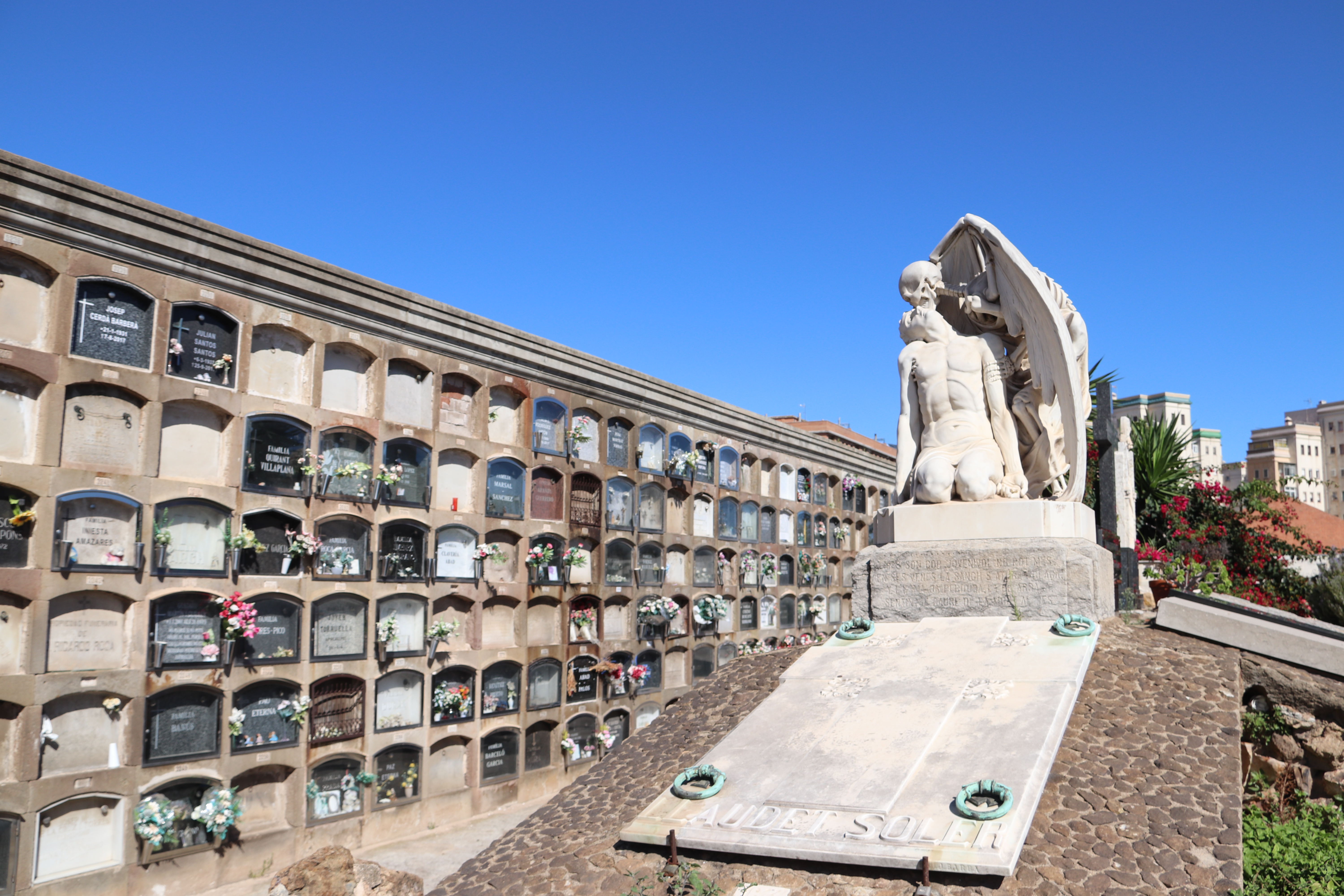 'The Kiss of Death' sculpture at the Poblenou Cemetery with niche tombs in the background