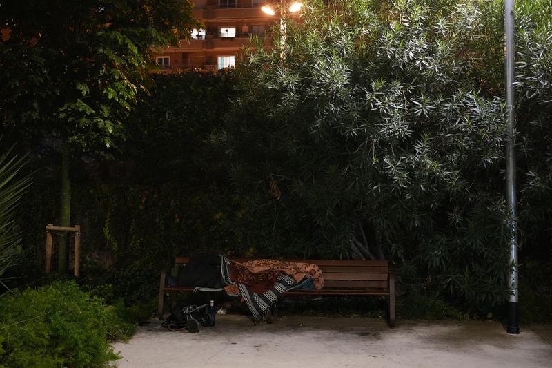 A person sleeps on a bench in Barcelona