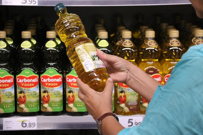 A shopper examines olive oil prices at a Barcelona supermarket