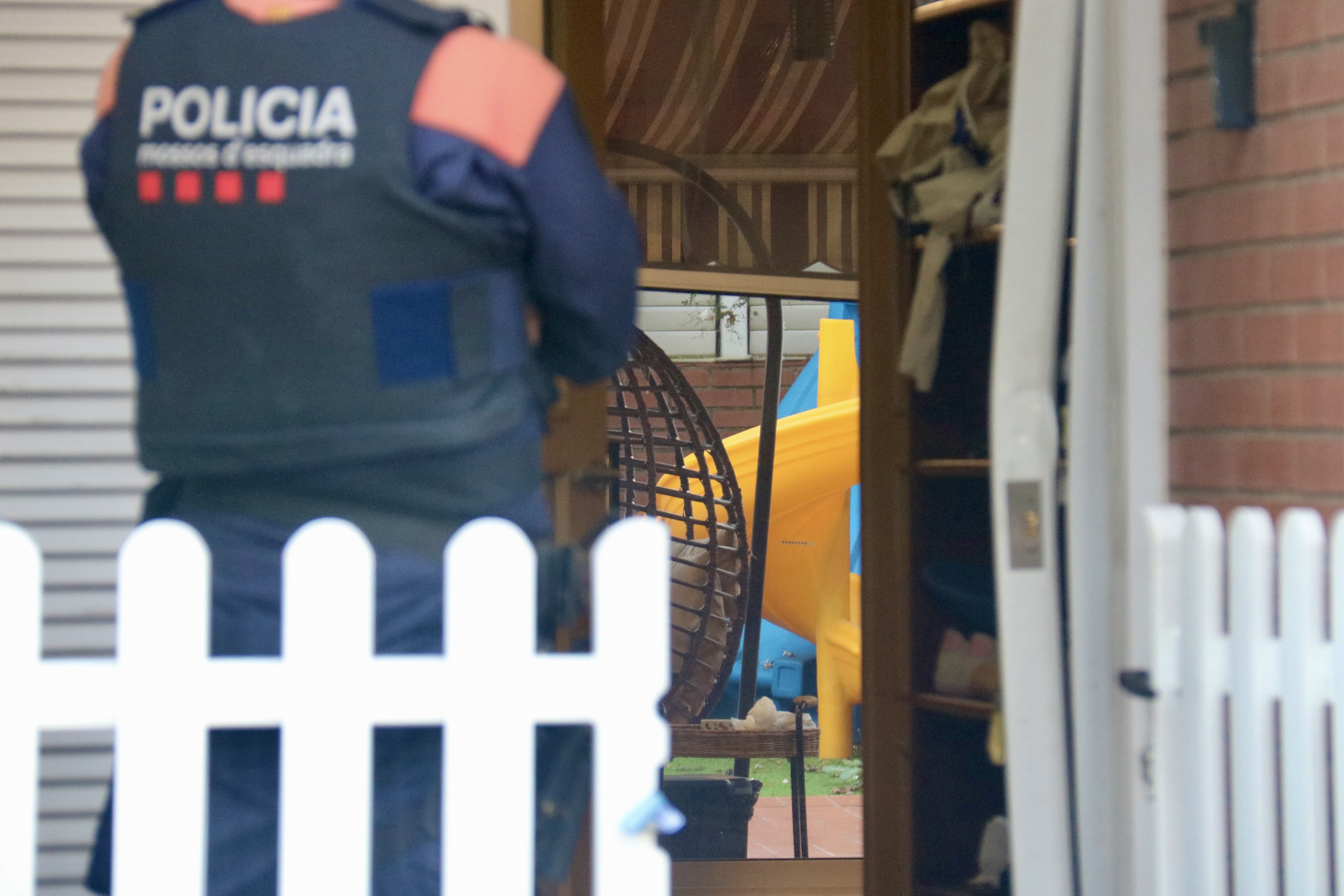 A police officer and the interior of a house being raided in Sabadell