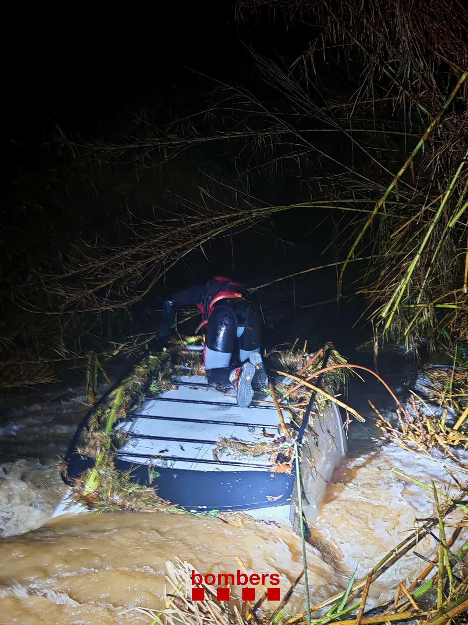 A firefighter stands on the roof of a van swept away by the Nova stream in Palau-sator