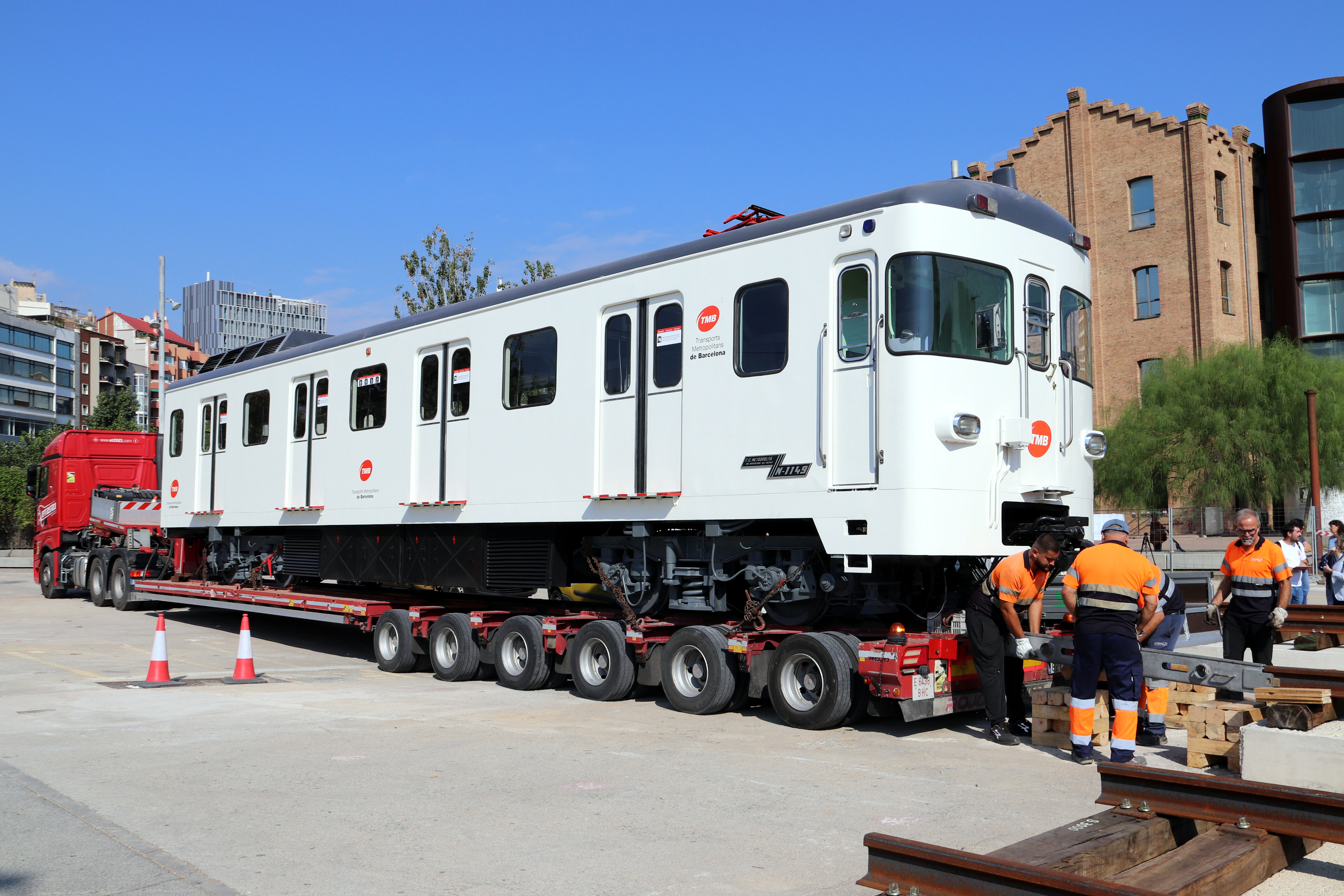 Workers install one of the restored carriages from the 1100 series of the Barcelona Metro at the esplanade in front of La Farinera del Clot, where it will be exhibited