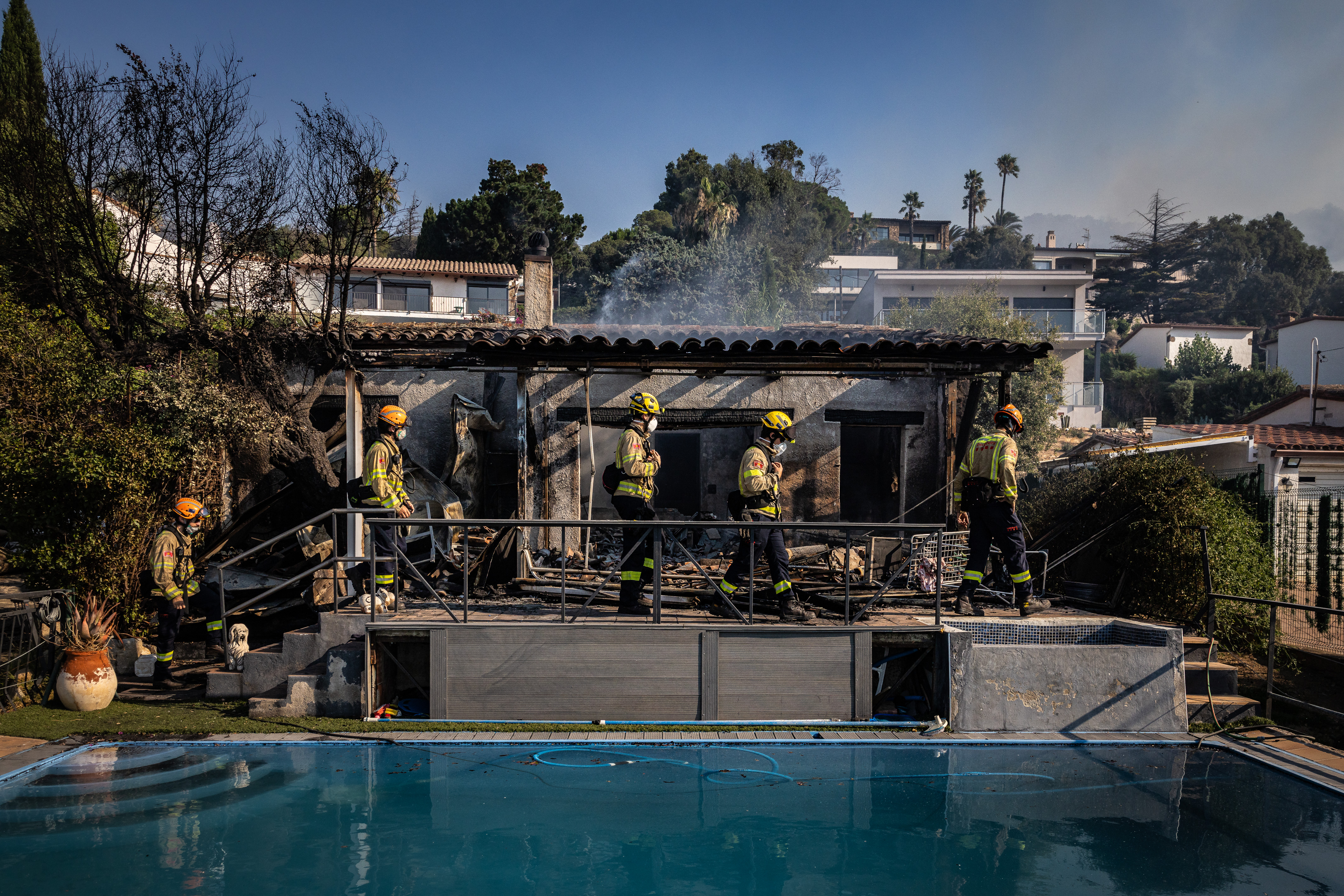 Firefighters at a fire-damaged house in a residential area of Calonge