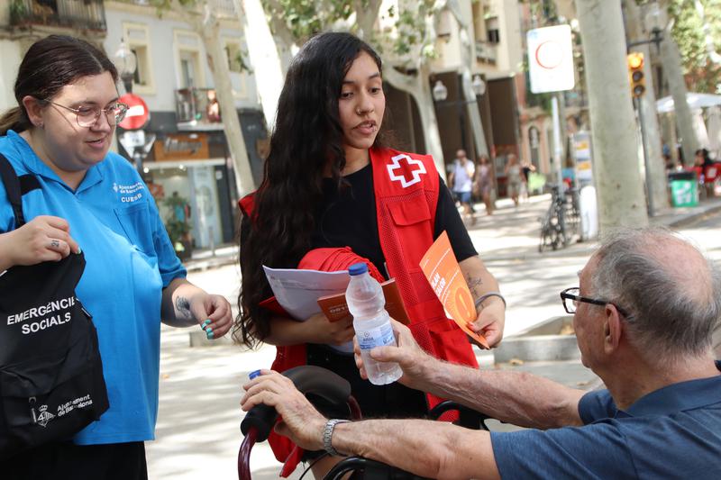 A member of the Red Cross hands out water and climate shelter information in Barcelona amid the ongoing heatwave