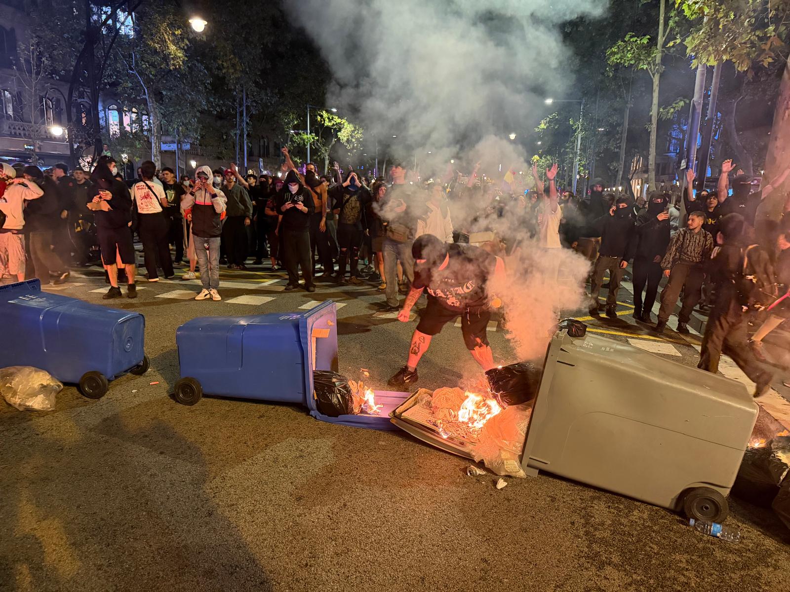 A person sets fire to rubbish containers during clashes with police