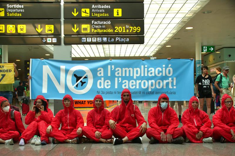 Environmental activists protest at Barcelona airport's Terminal 1 against the expansion dressed in red