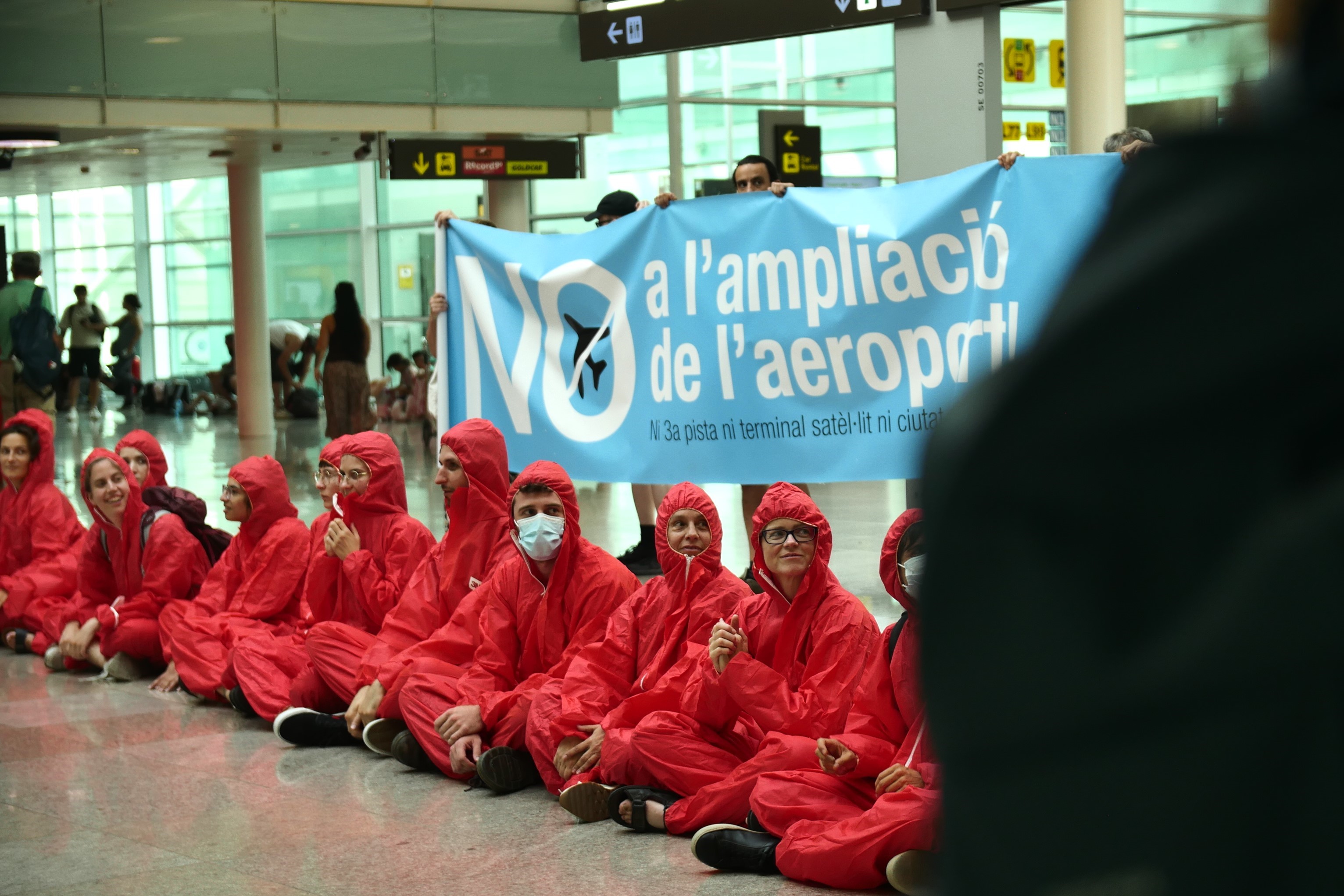 Environmental activists protest at Barcelona airport's Terminal 1 against the expansion dressed in red