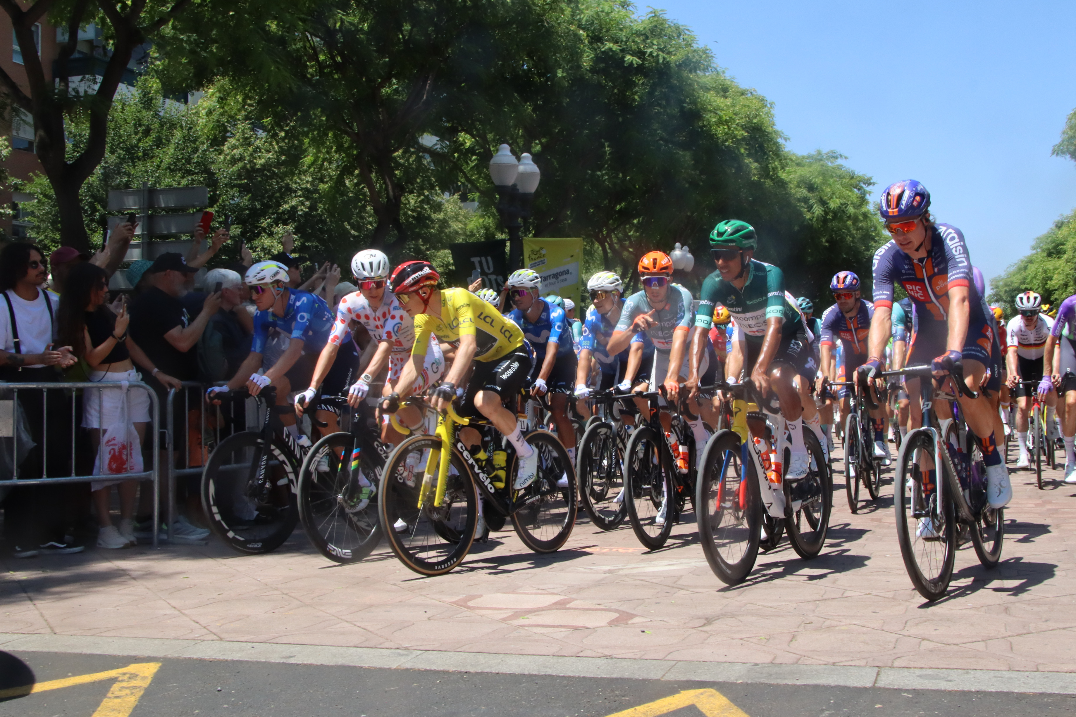 Moment of the neutralized start of the second stage of the Tour de France 2026 in Tarragona, with Jonas Vingegaard (yellow jersey) conversing with Tadej Pogacar (white jersey with red dots)