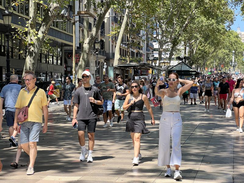 Tourists walk down La Rambla boulevard on August 4, 2022