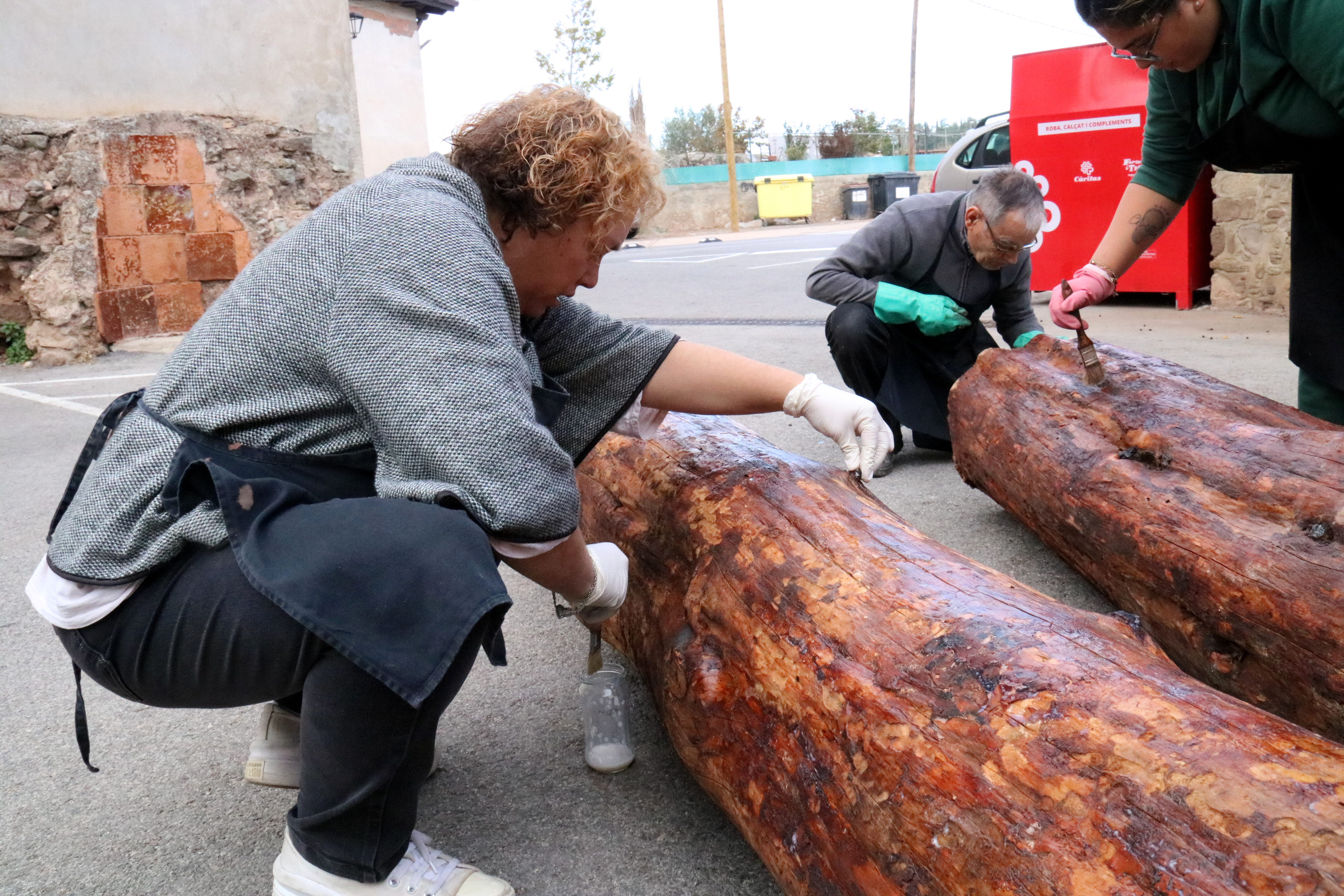 Usuaris d'Ampans treballen netejant el tronc cremat per convertir-lo en tió de Nadal