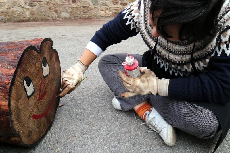 Painting the face of 'tió' on a charred tree trunk 