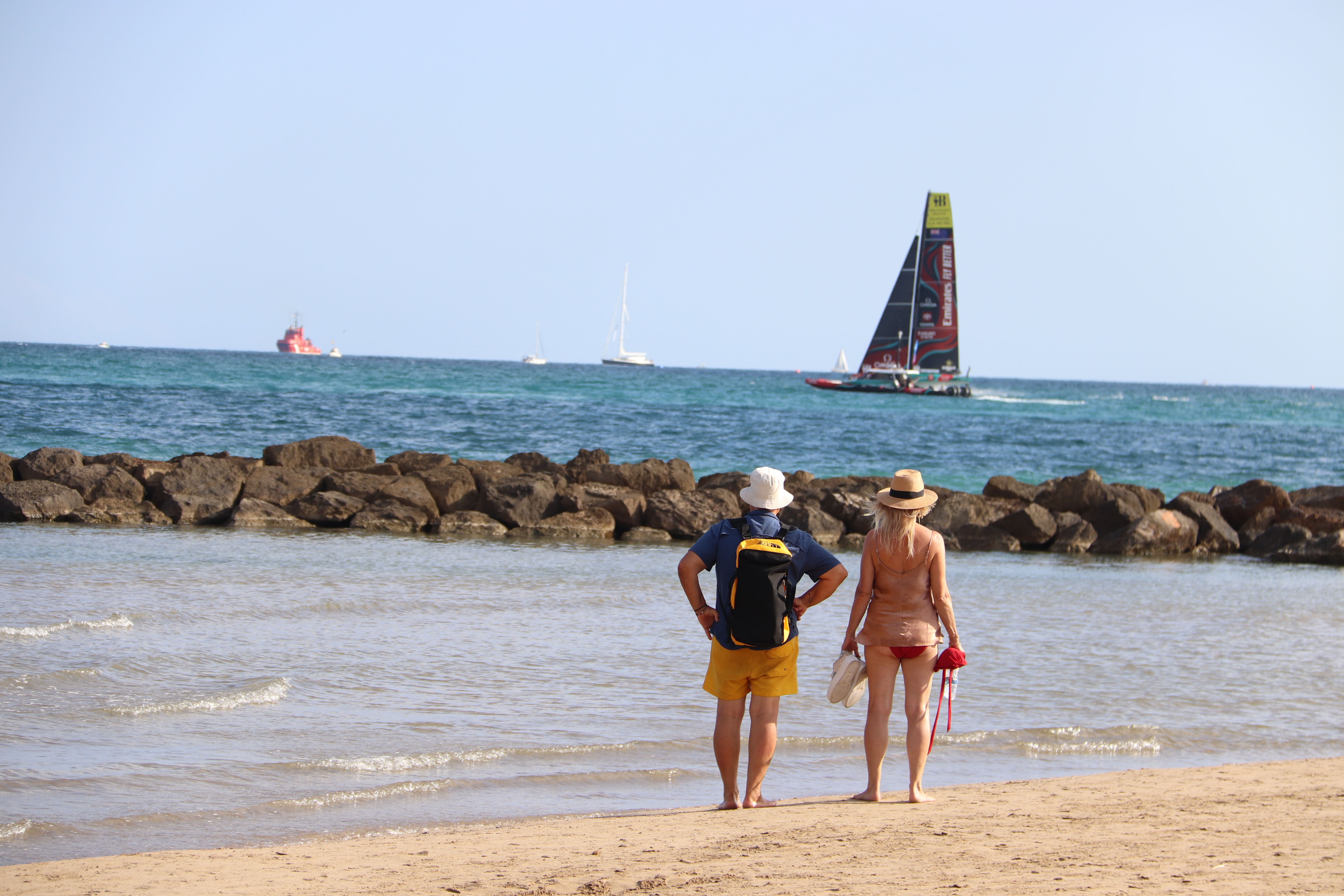 Spectators on the beach in Vilanova i la Geltrú watch an America's Cup boat during an official practice on September 14, 2023