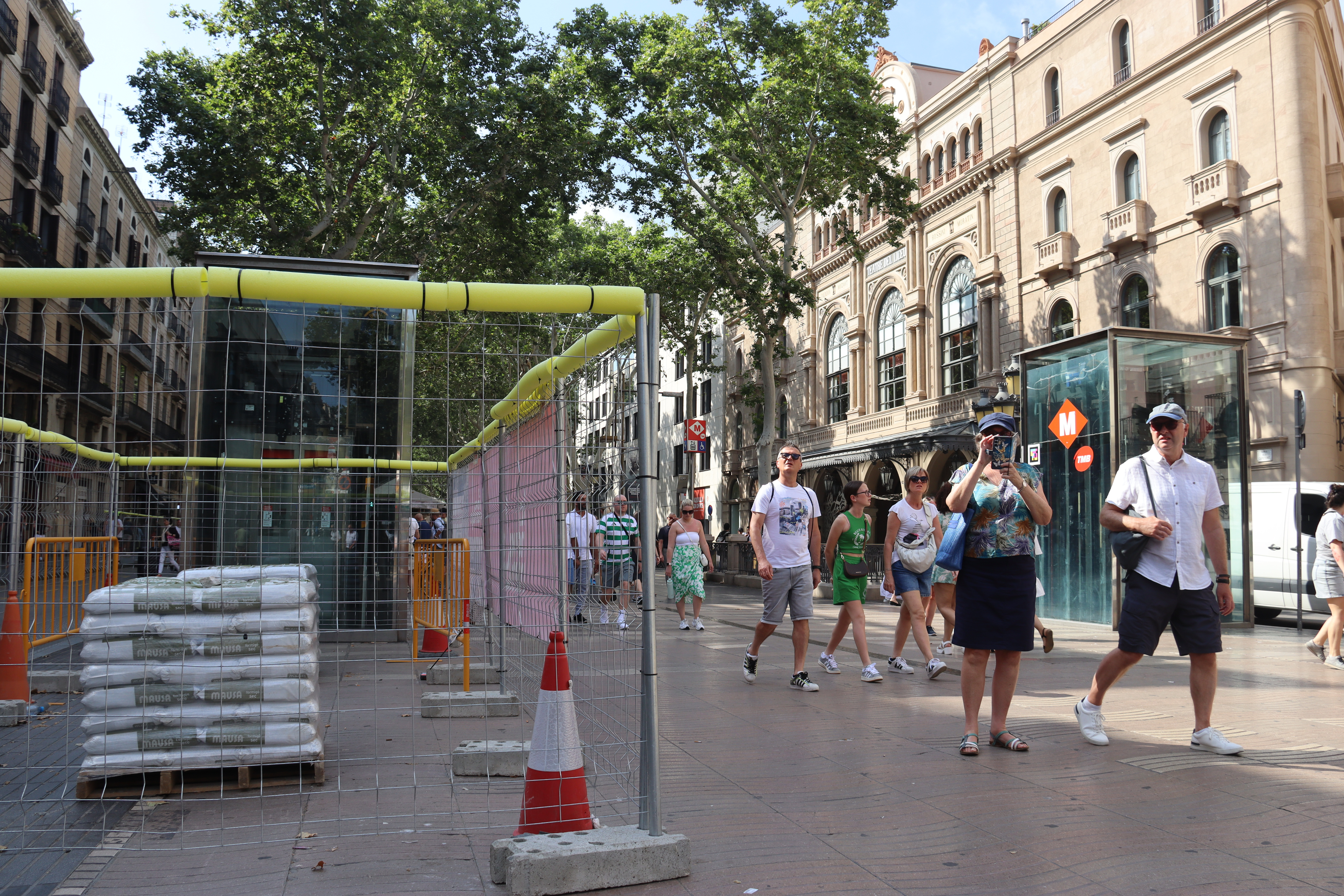 Barcelona tourists walking on La Rambla boulevard with the Liceu opera hall behind them in June