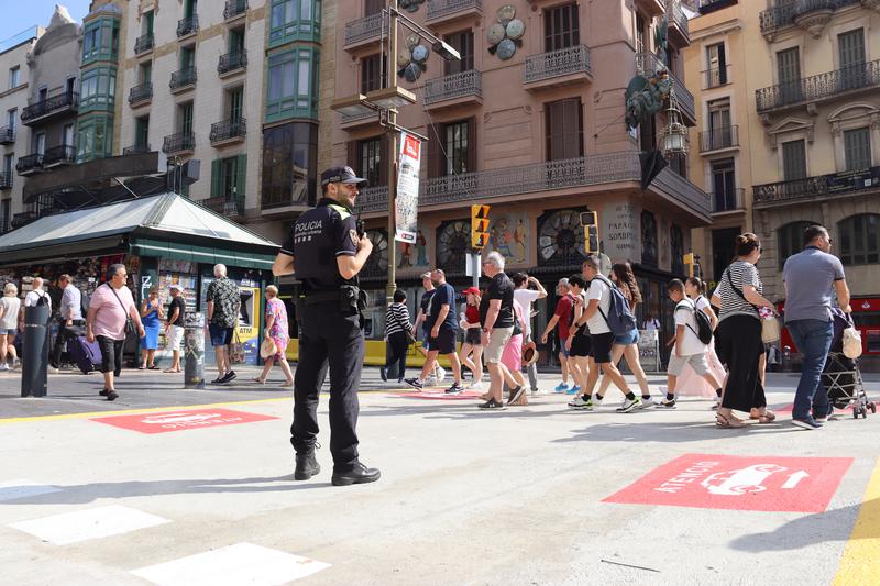 A police observes pedestrians walking in La Rambla boulevard in June 2024 in Barcelona