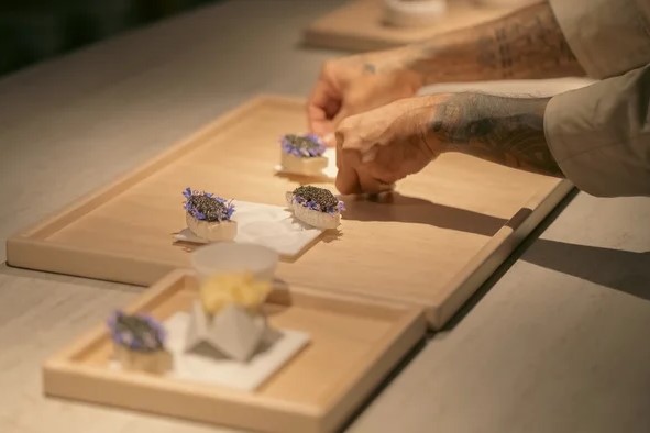 A chef preparing a dish at Somni Restaurant