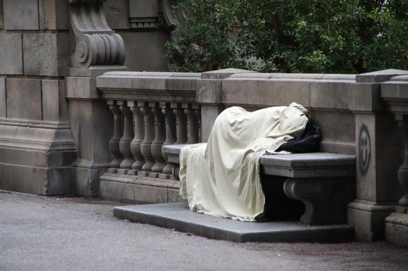 A homeless person on a bench in Plaça Catalunya.