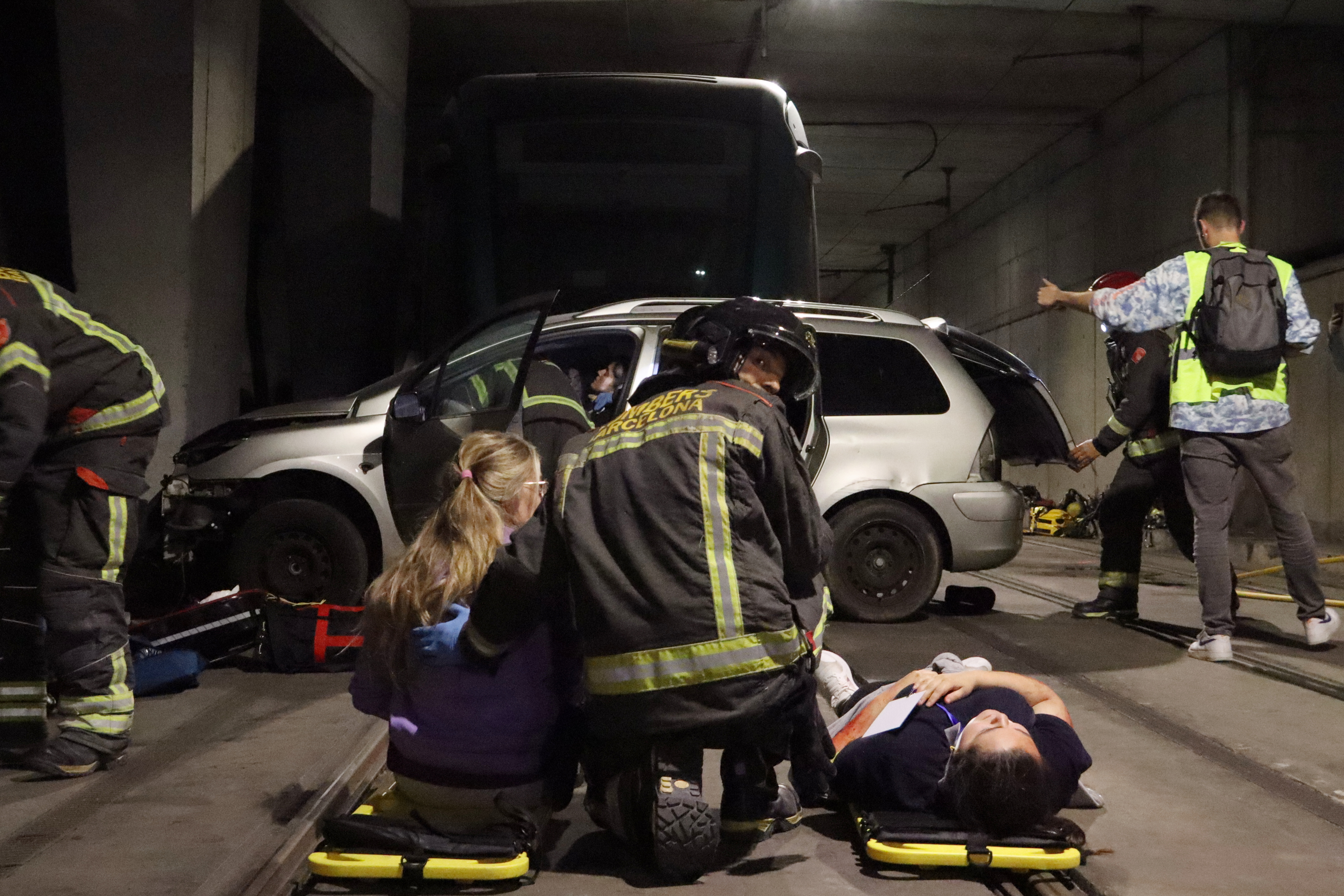 Firefighters helping actors pretending to be injured during tram accident drill.