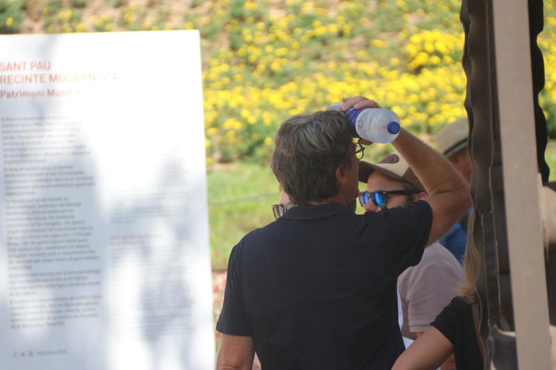 A man places a bottle of cold water on his forehead to cool off from the heat.