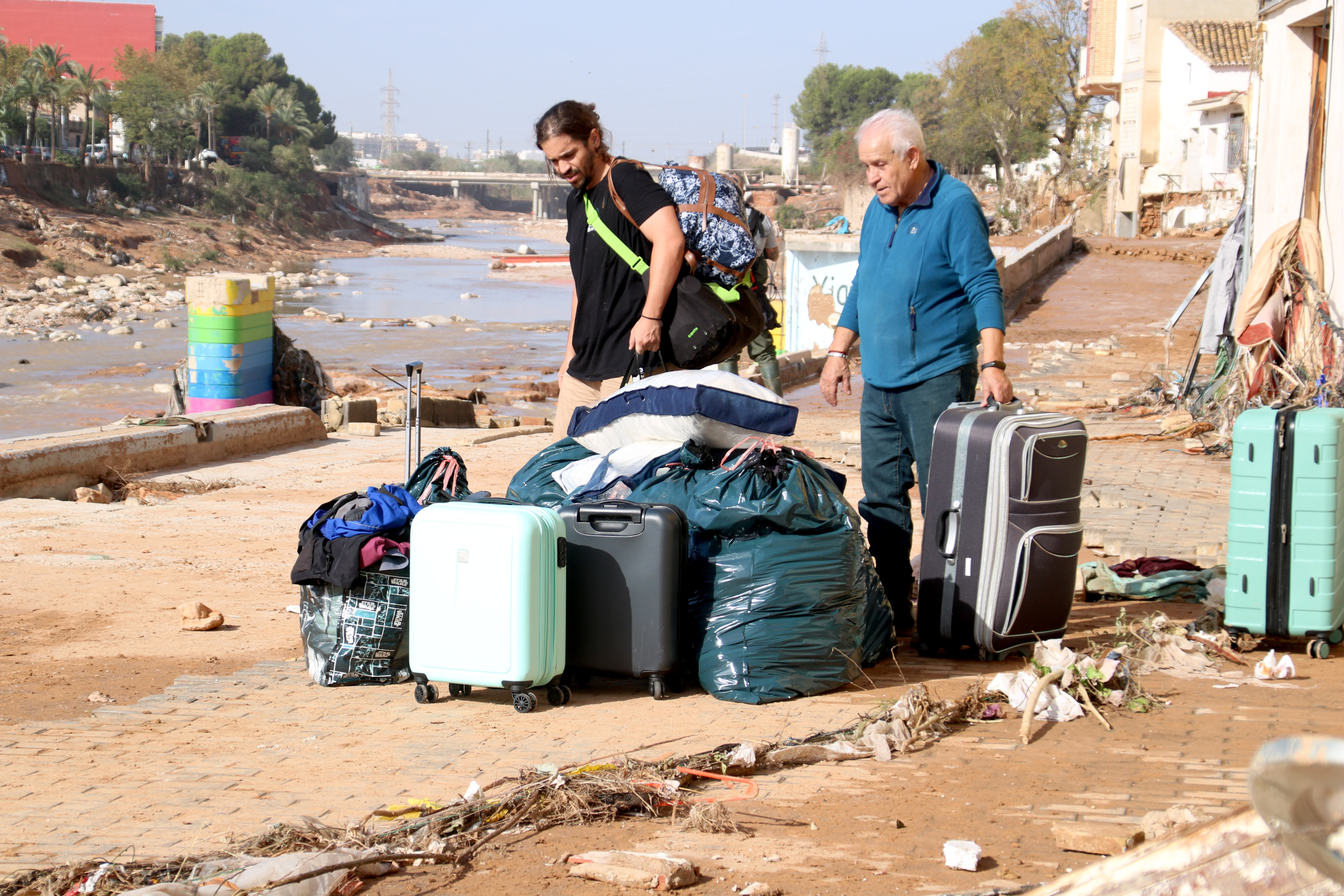 A father and son prepare bags to leave their home destroyed by the floods in Picanya