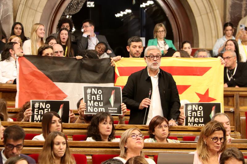 Far-left CUP MP Carles Riera speaking in the Catalan parliament while members of the party display a Palestinian and a Catalan pro-independence 'estelada' flags on October 25, 2023