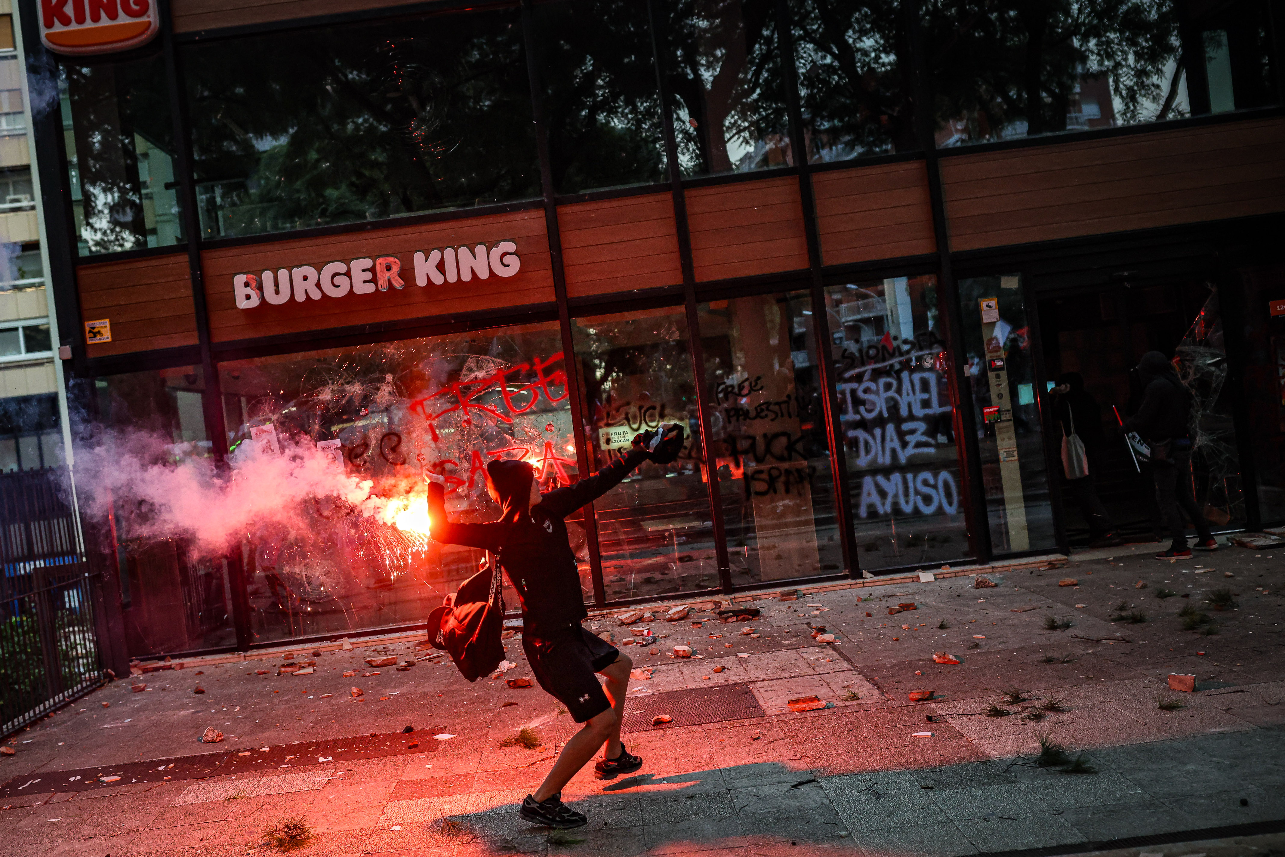 A person about to throw a lit object at a Burger King during a pro-Palestine demonstration in Barcelona