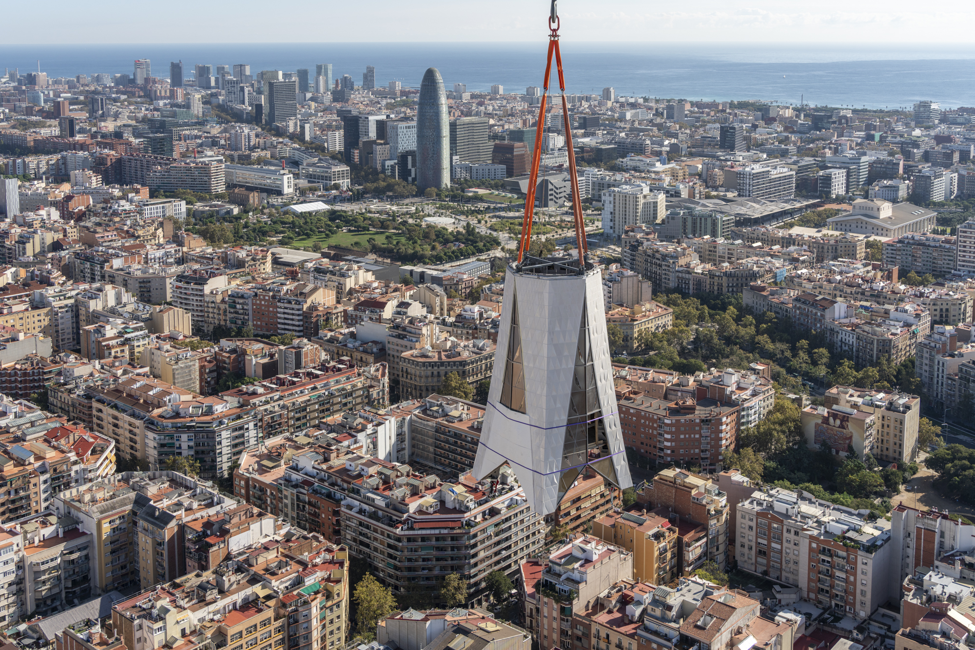 One of the parts of the cross of the Tower of Jesus Christ of the Sagrada Família with Barcelona behind