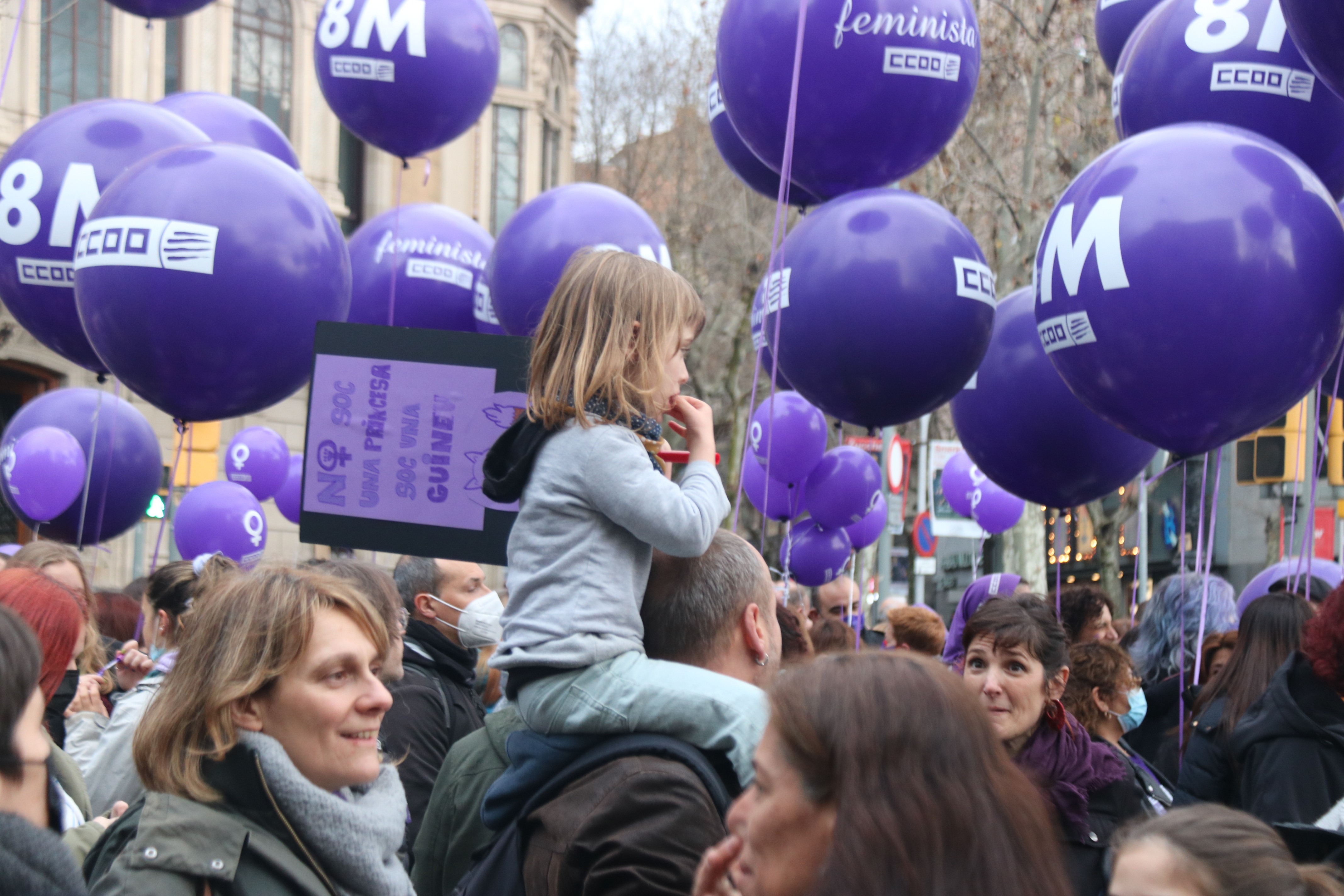 A little girl on her father's shoulders at the 2022 International Women's Day protest in Barcelona