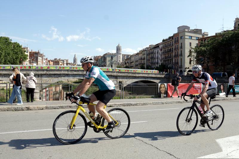 Two cyclists ride through Girona's Plaça Catalunya