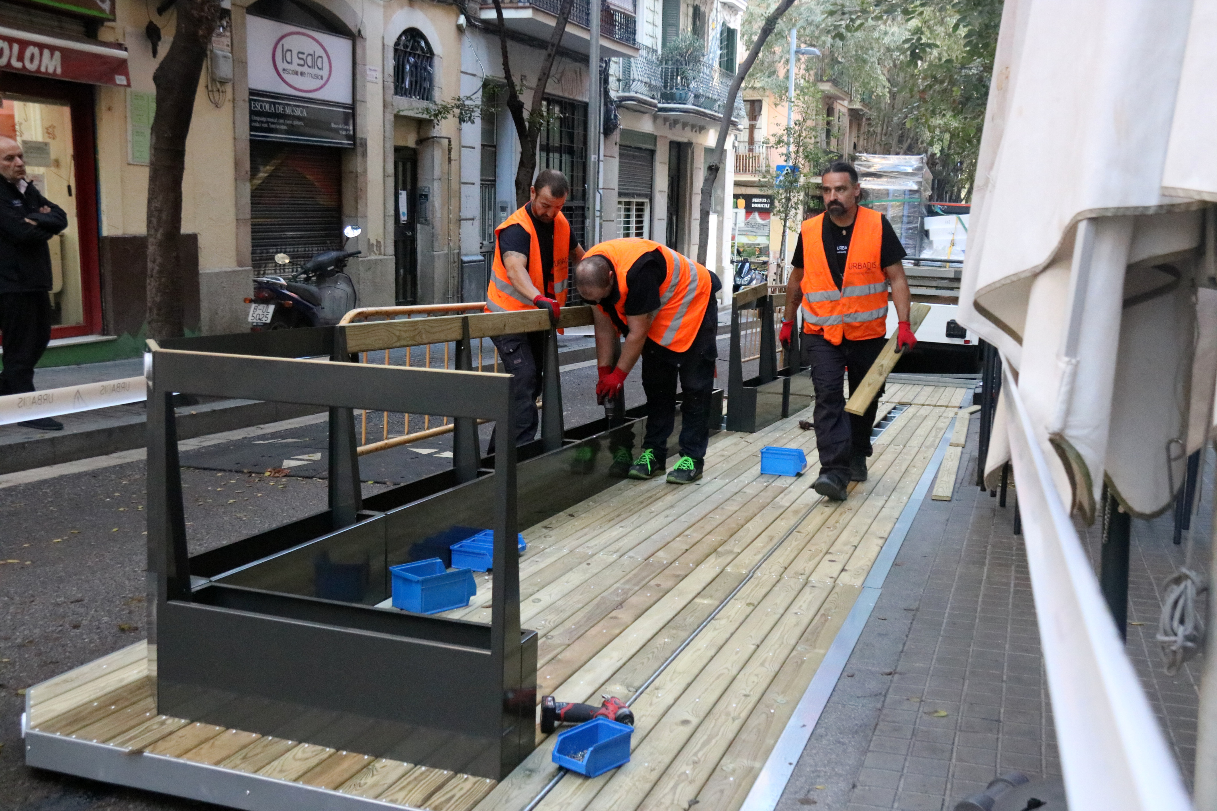 Workers install a platform onto a newly-approved outdoor dining space in Barcelona