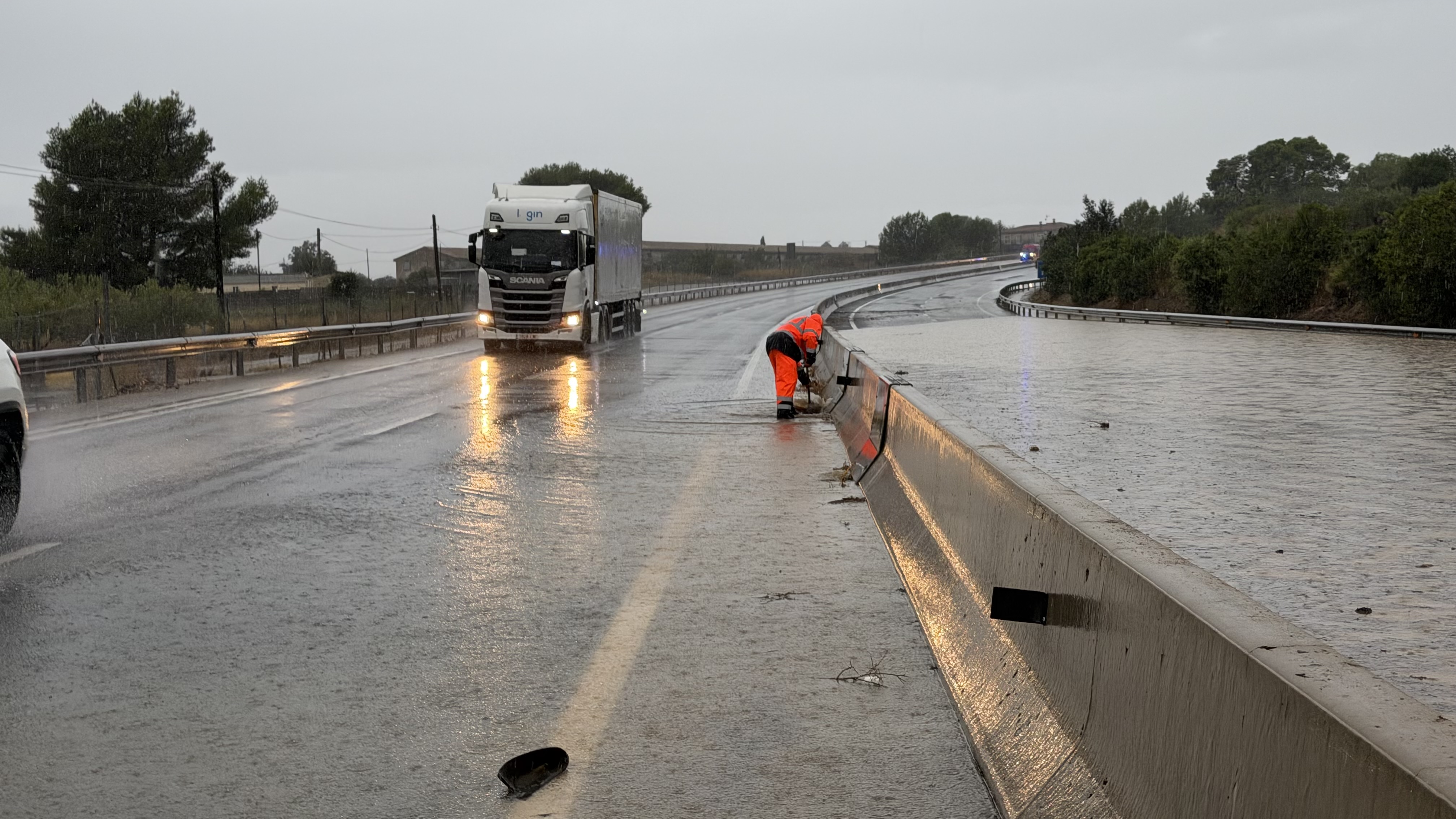 A road maintenance worker attempts to clear a flooded lane on the C-42 between Tortosa and L'Aldea.