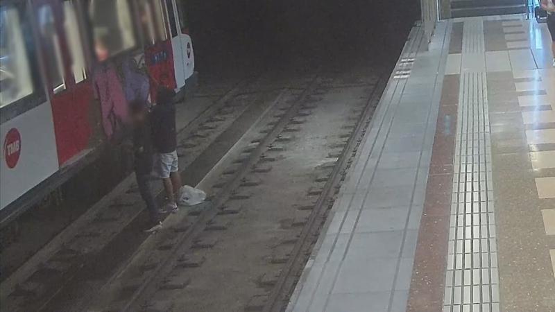 Screenshot of a security camera on Barcelona's metro where two people are seen painting graffiti on a train