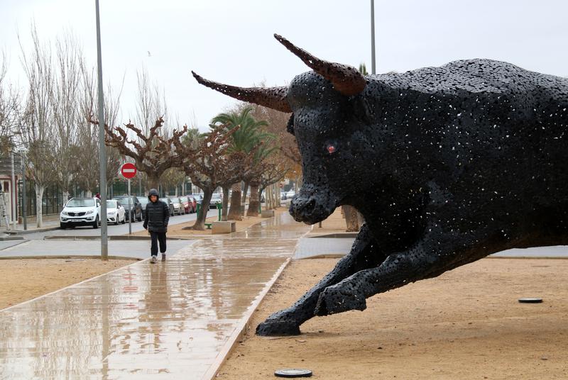 A person walks by a sculpture of a bull in Amposta, southern Catalonia