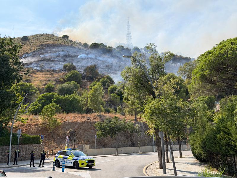 Image of the Collserola fire, with a Barcelona police vehicle blocking access