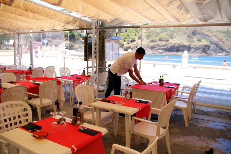 A waiter sets the tables in a restaurant in Portbou, Girona.