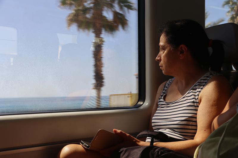 A woman looking out of a train window at the Maresme coast