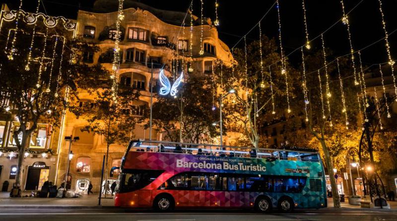 A Barcelona Christmas Tour bus passes in front of Antoni Gaudí's La Pedrera building on Passeig de Gràcia