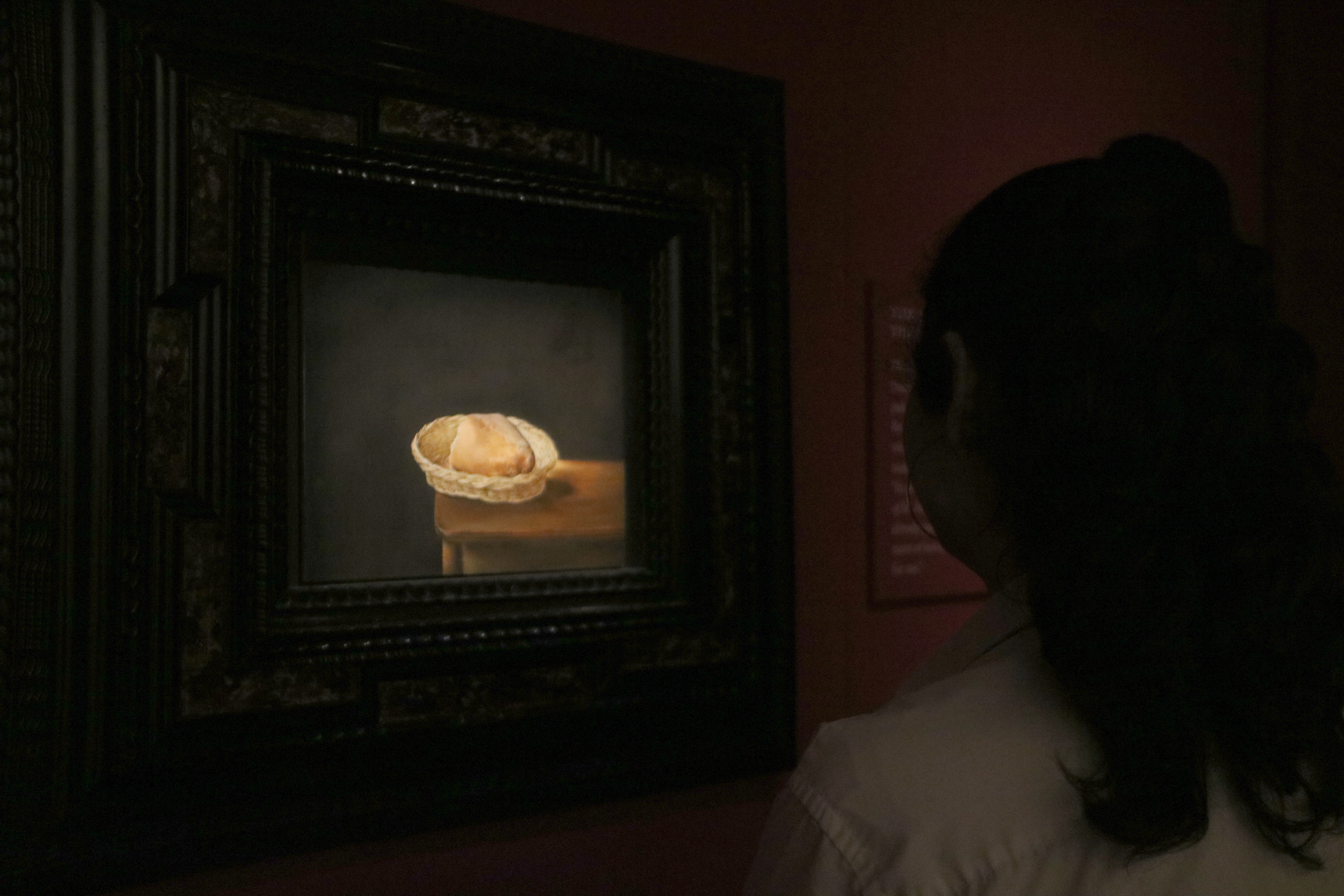 A woman looks at Salvador Dalí's painting, 'Basket of Bread'
