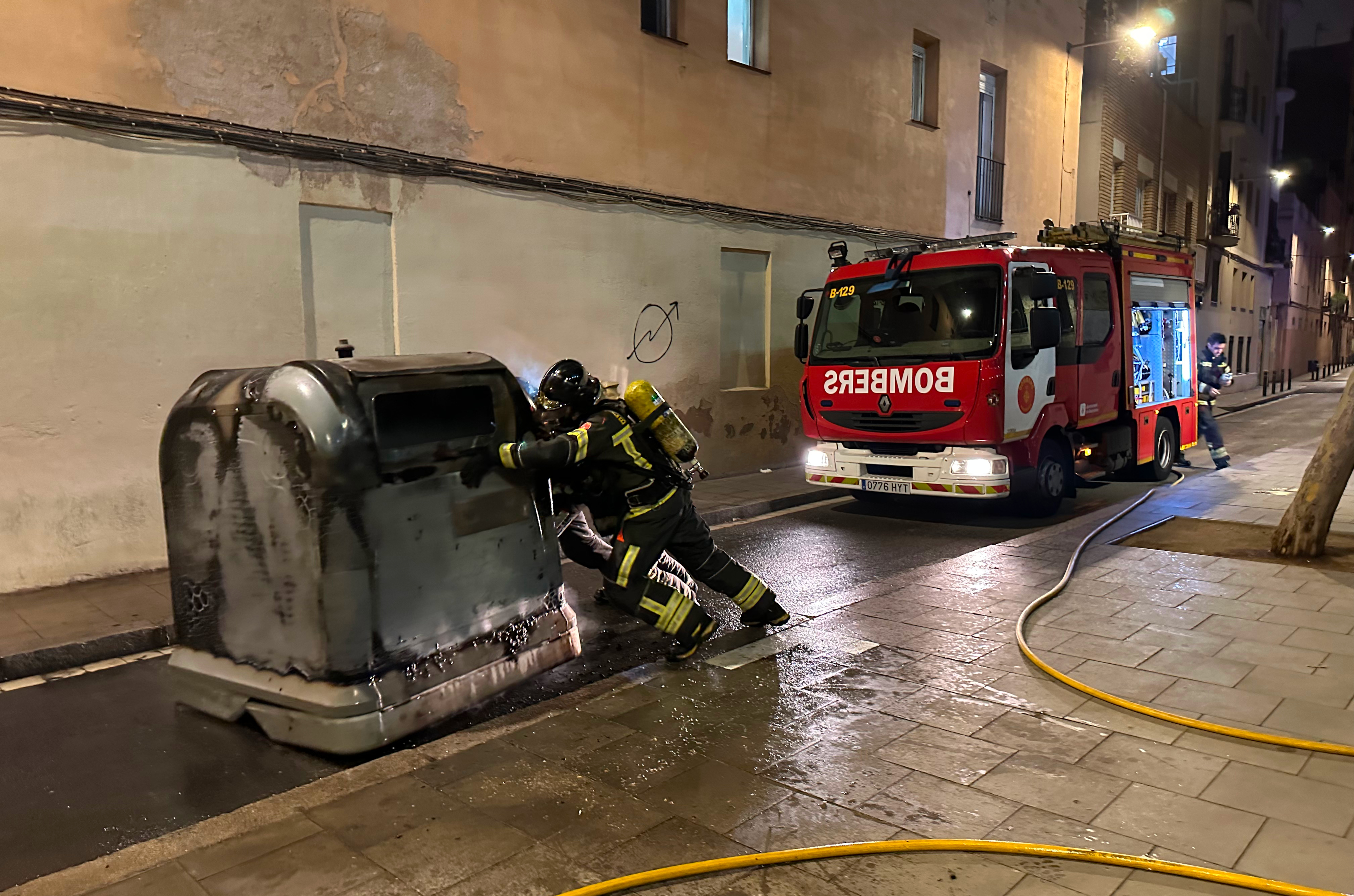 Barcelona firefighters move a burned container in the neighborhood of Gràcia in an archive picture