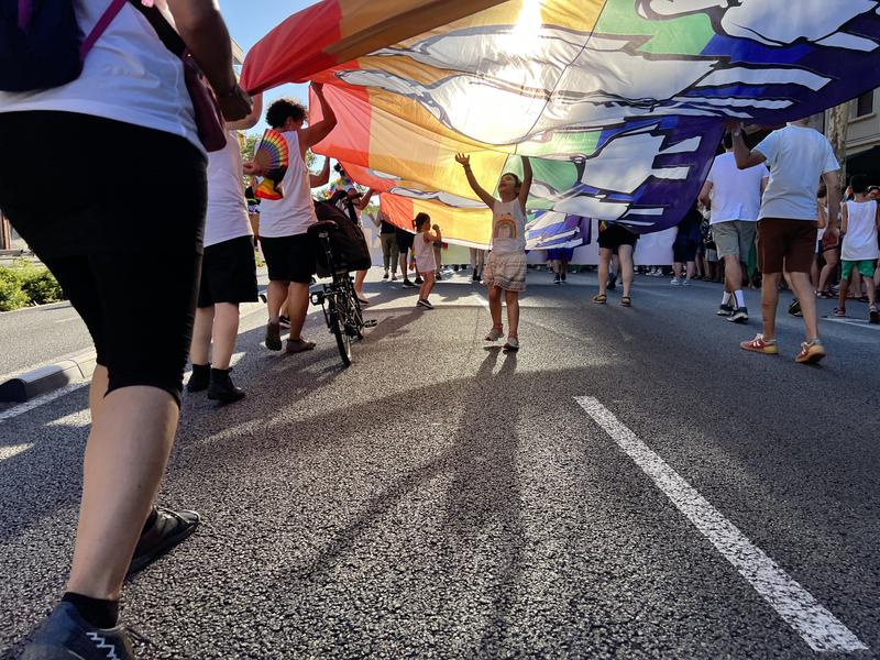 Child reaching for rainbow banner during 2023 Barcelona Pride Parade