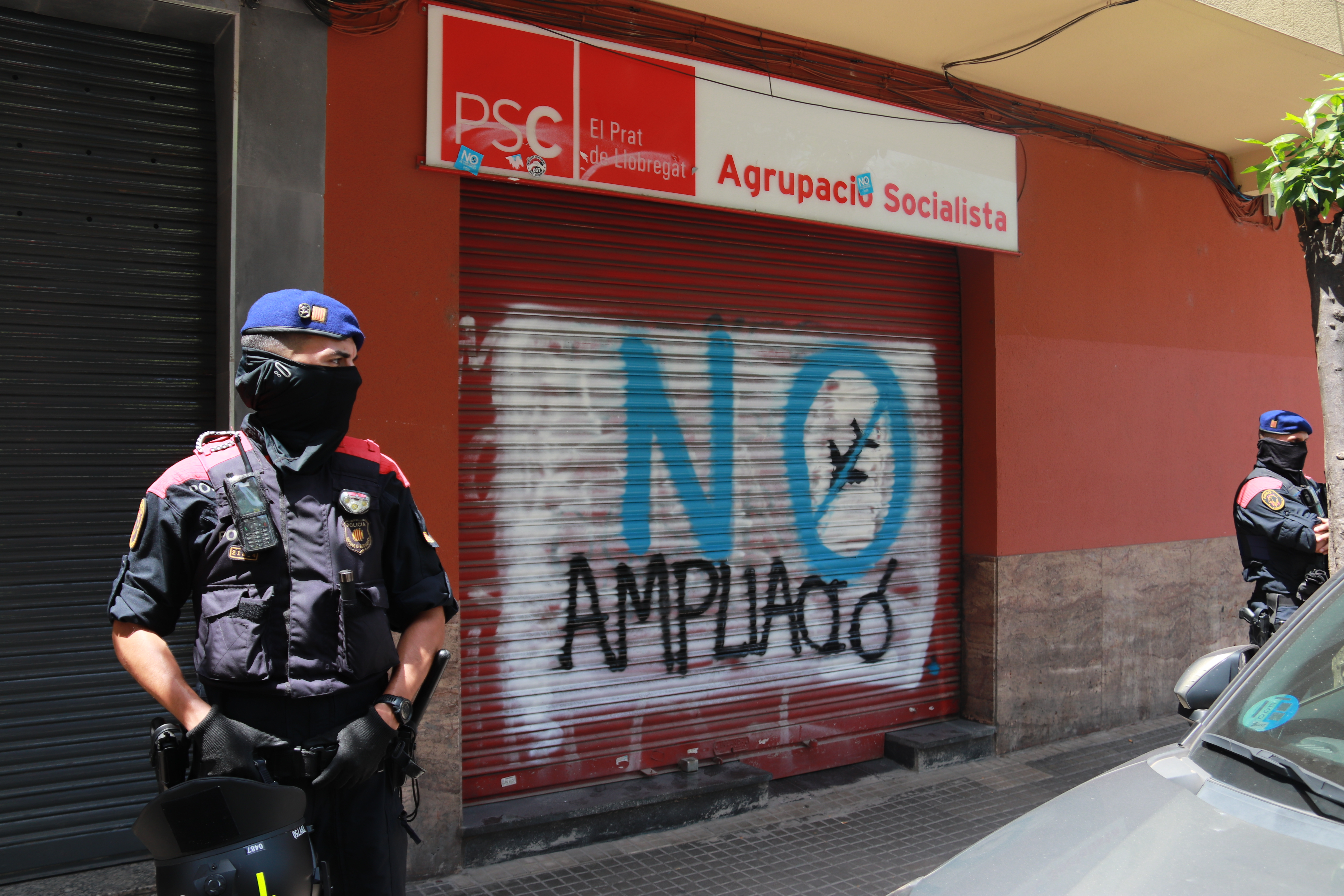 Catalan police guard the Socialists' office in El Prat de Llobregat, where anti-airport expansion graffiti has appeared.