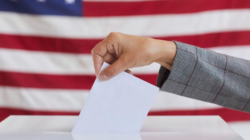 An illustrative image of a voter casting a ballot with a U.S. flag in the background