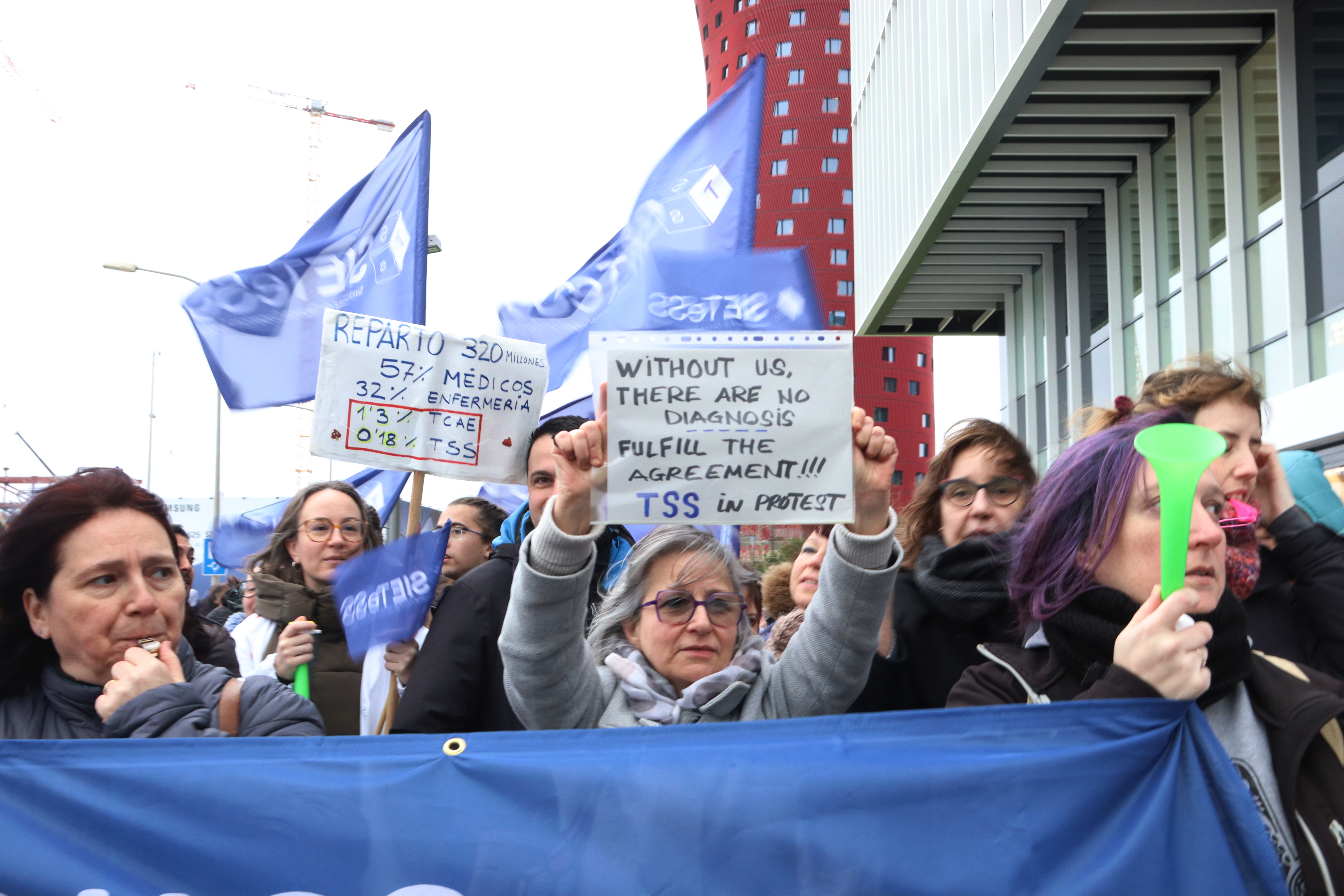 Tècnics sanitaris protesten davant dels congressistes del Mobile World Congress (MCW) en la primera jornada de vaga, amb cartells sobre les millores salarials que reclamen i reivindicant el seu paper en el procés diagnòstic -en anglès-.