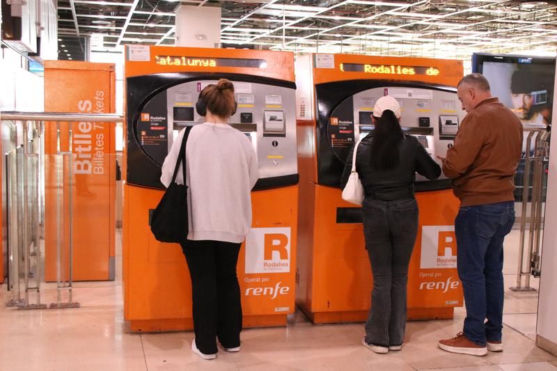Users of the Rodalies commuter rail service buy tickets