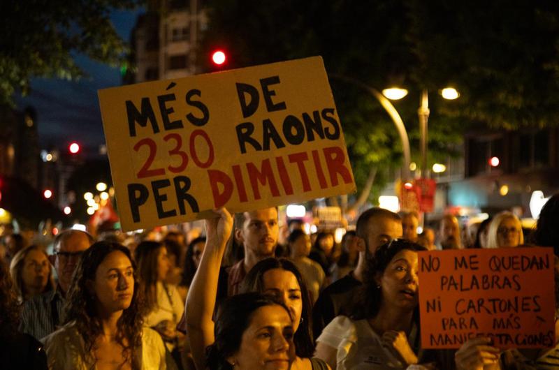 Protesters hold up signs against the Valencian regional president