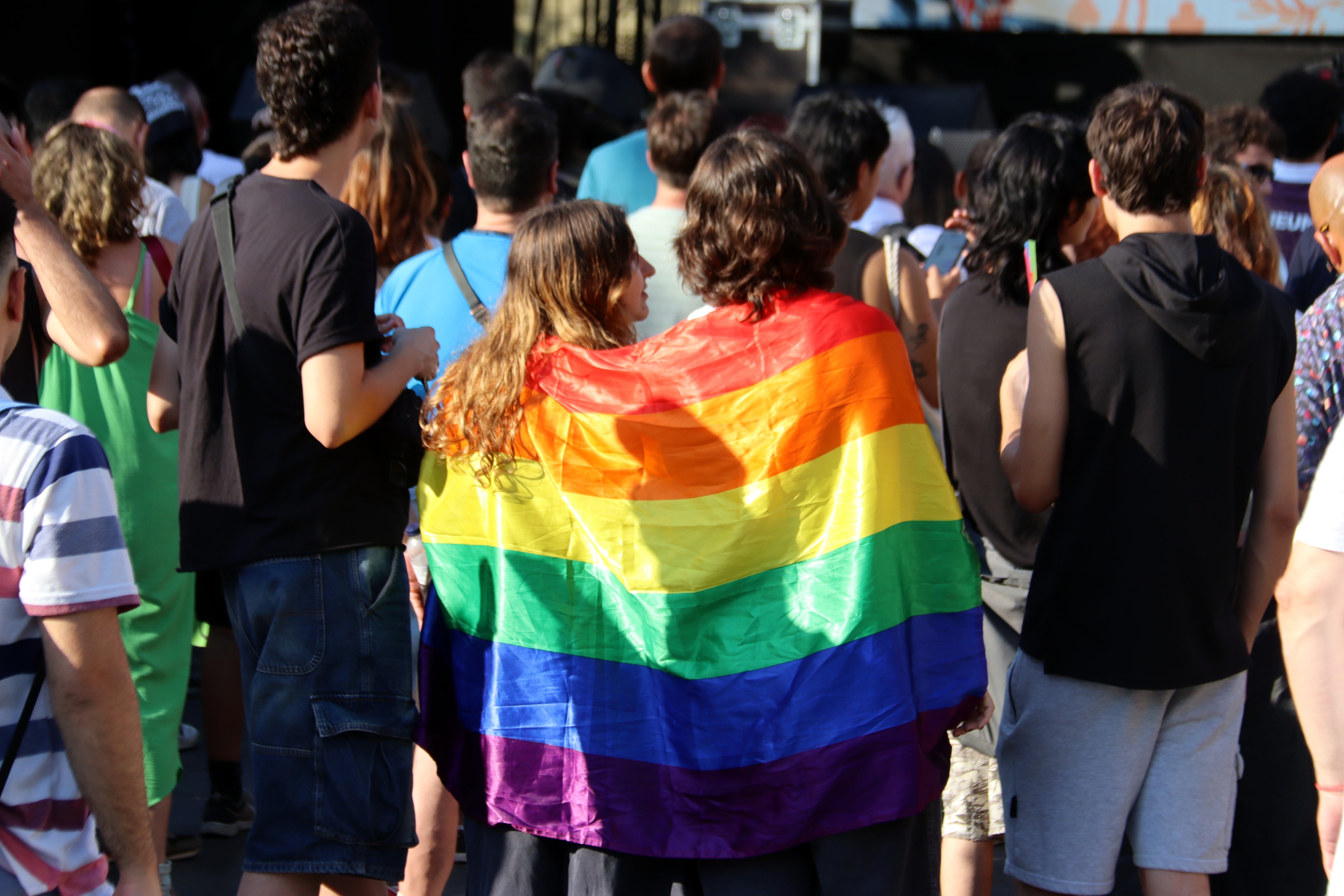 Two people wrapped in a rainbow flag at Pride Barcelona