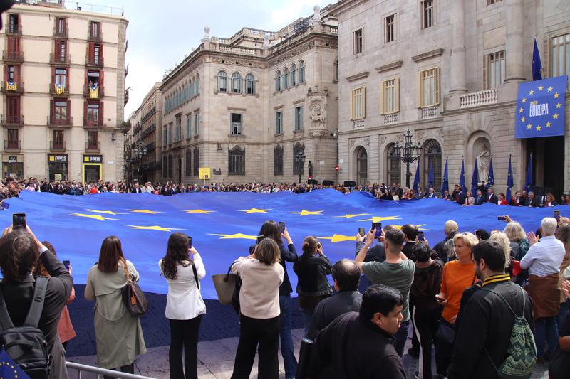 A giant European flag is held by people in Plaça Sant Jaume to celebrate Europe Day