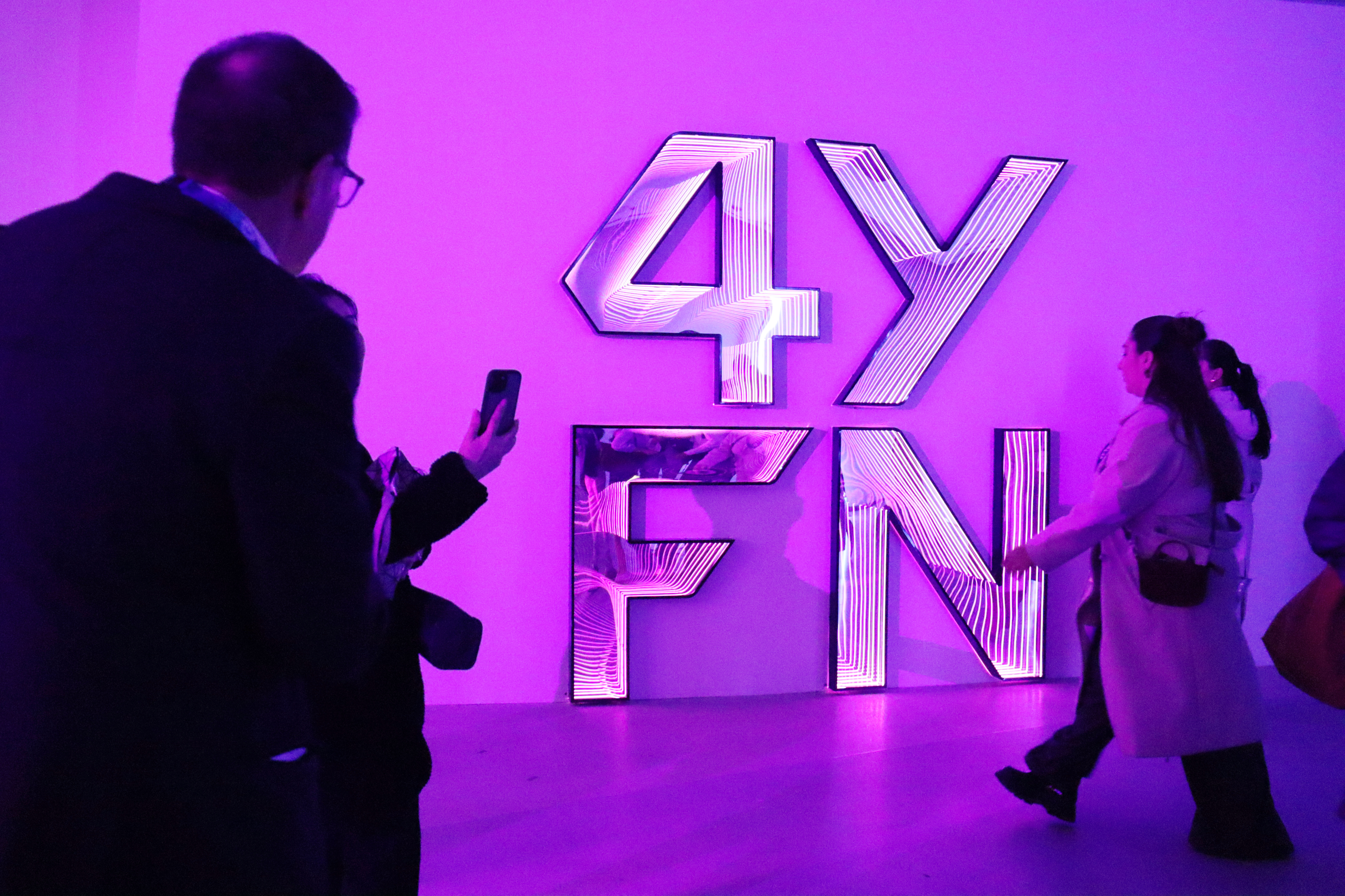 Several MWC attendees walk in front of a 4YFN logo during the tech fair in Barcelona