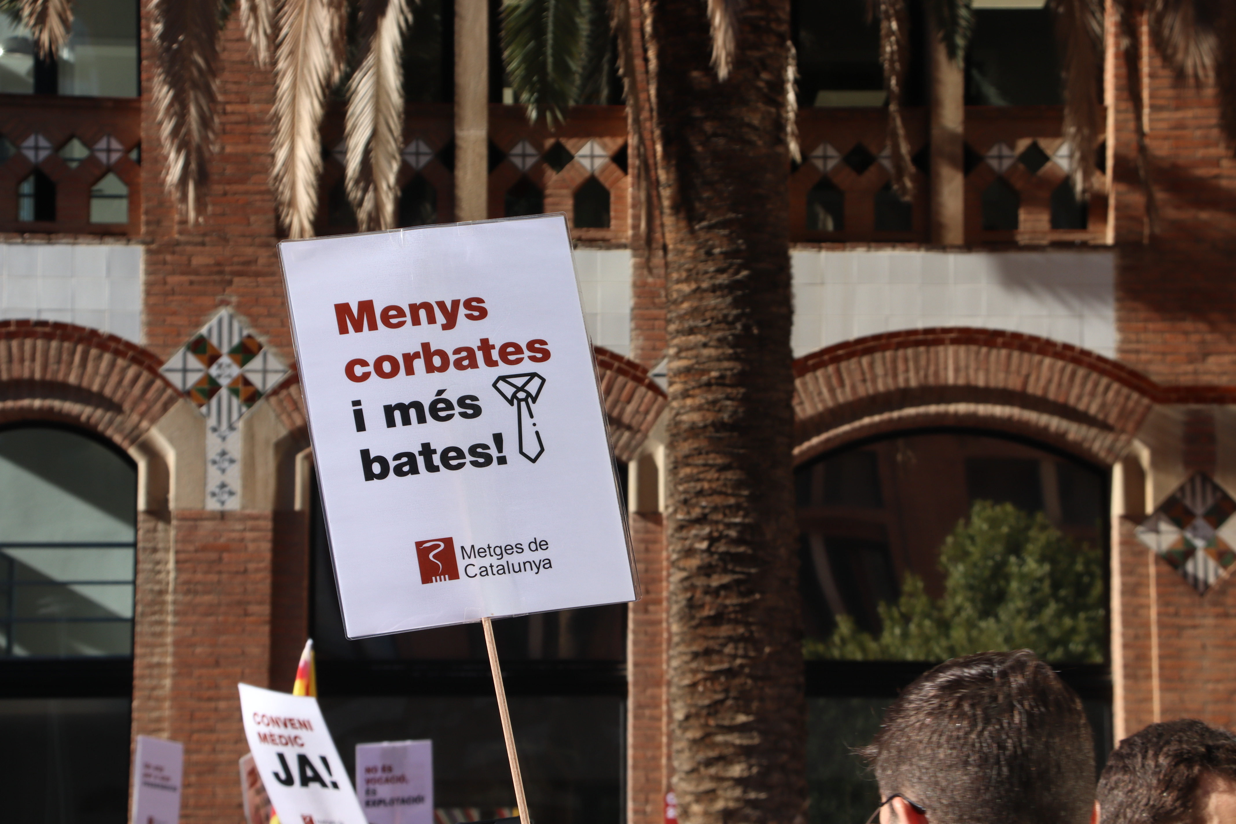 A placard reading “Less suits, more scrubs” at a demonstration called by Metges de Catalunya outside the Department of Health