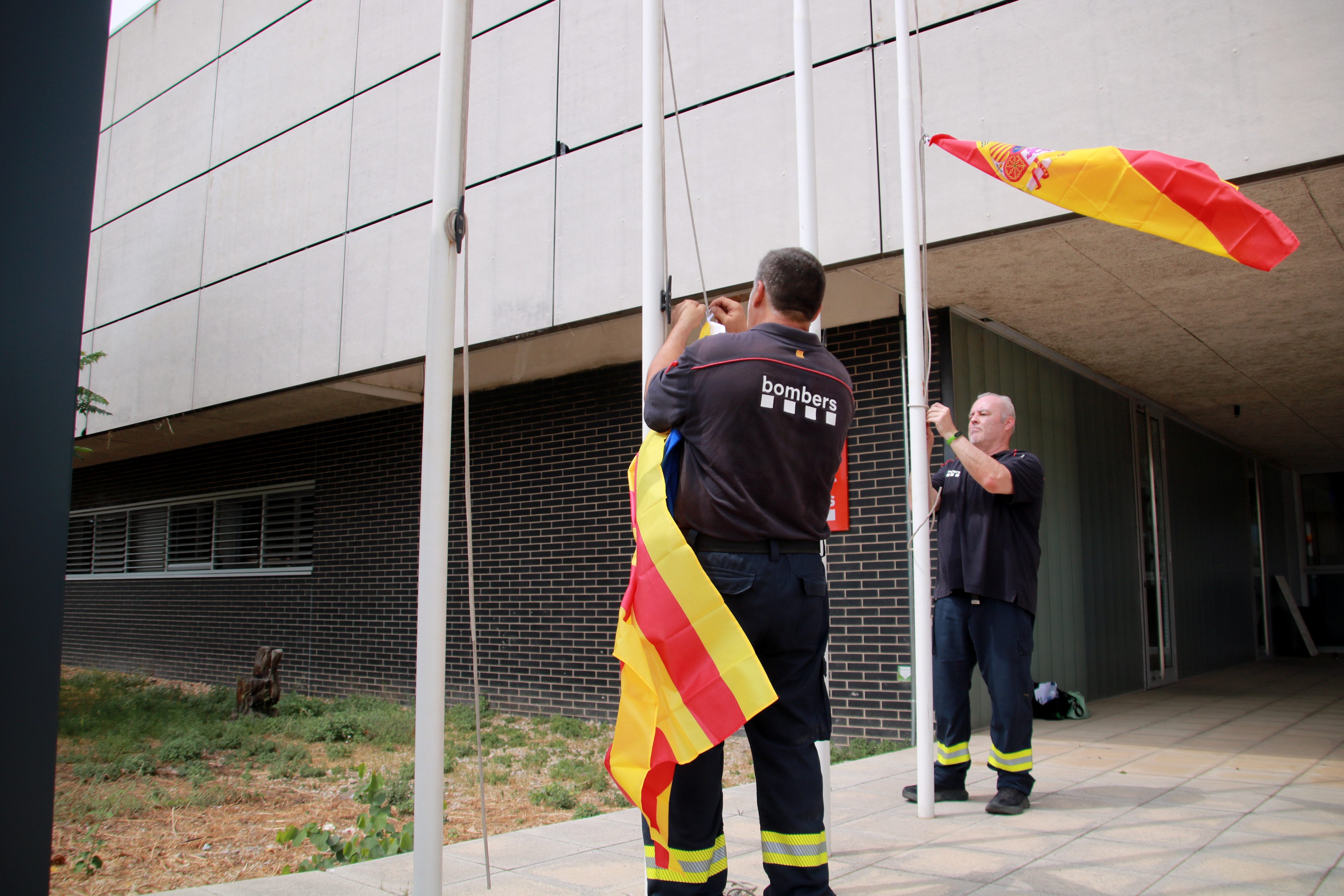 Firefighters lower the flag to half-mast in mourning for the death of the firefighter who died in Paüls wildfire
