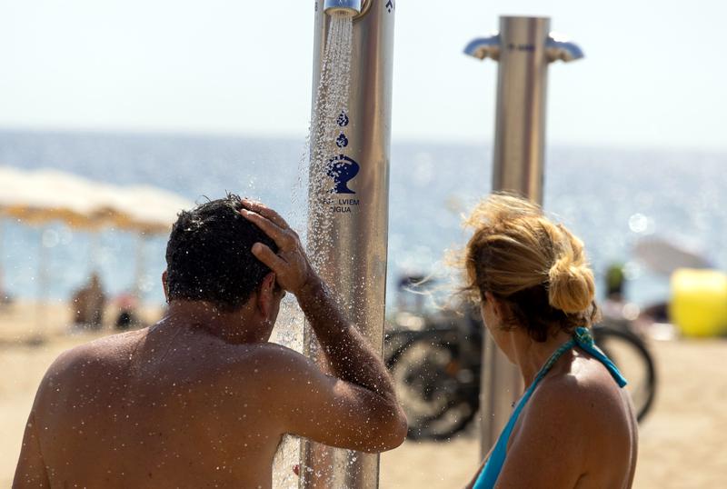 Two people have a shower at a Barcelona beach on April 7, 2023